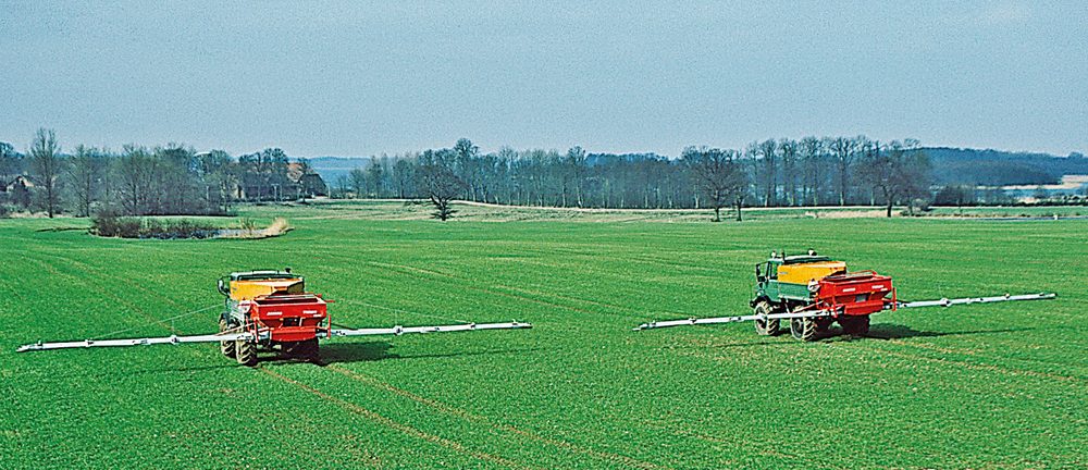 Zwei 18-m-TURBO-Streuer hinter Unimogs auf einem Großbetrieb in Schleswig-Holstein.